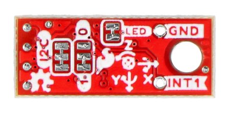 The red IMU sensor micromodule lies upside down on a white background.